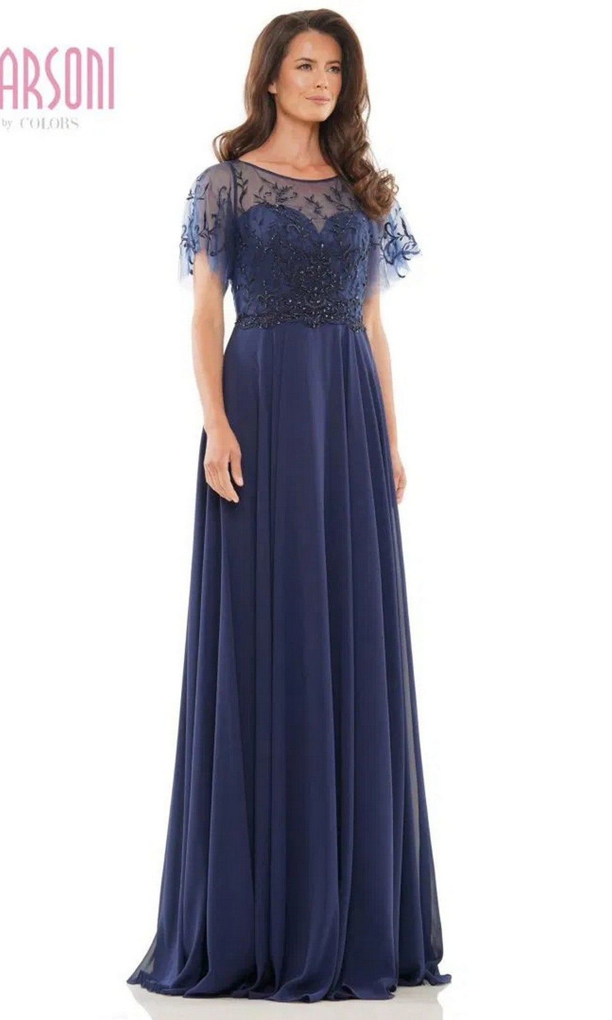 A woman models the Marsoni M323 long formal dress in navy, featuring a floor-length A-line chiffon skirt, sheer short sleeves, and a floral beaded bodice, set against a white background.